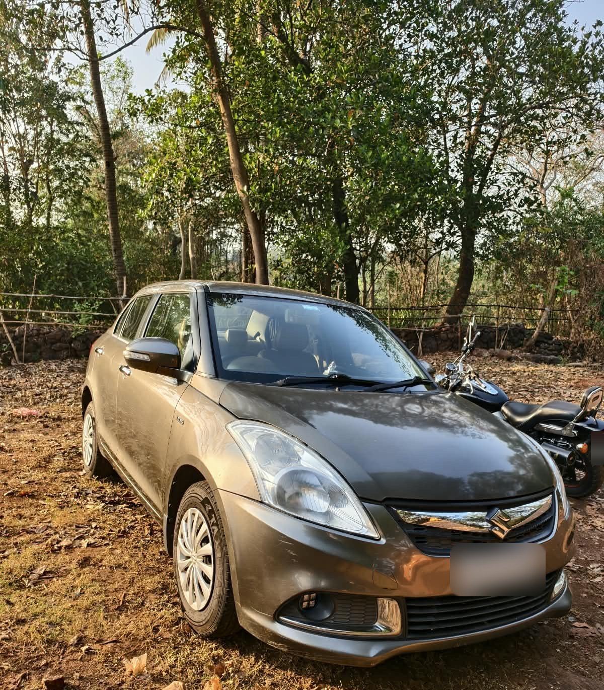 Grey Maruti Suzuki Dzire under trees